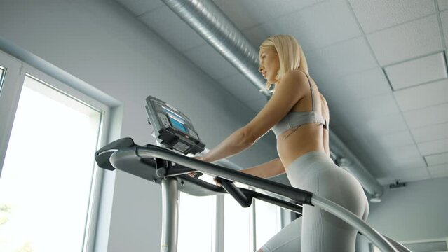 Woman walking on climbing machine in a fitness club, gym, cardio workout