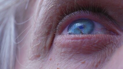 Macro close-up of a senior man's blye eyes staring at clouds in the sky. Extreme detail of person's...