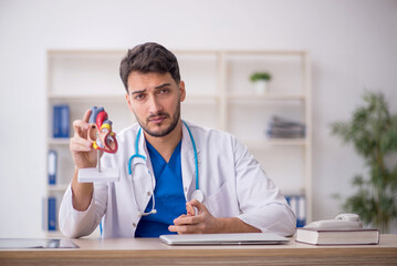 Young male doctor cardiologist sitting at the hospital