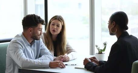 Young multiethnic couple buyers clients shake hand of African female real estate agent after contract signing. Make commercial deal, take loan finish meeting with professional advisor in bank office