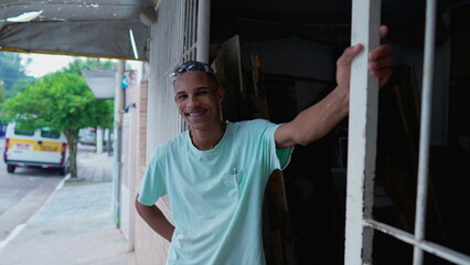 One happy black Brazilian young man standing by sidewalk street smiling at camera. Authentic real life from South America portrait with friendly expression