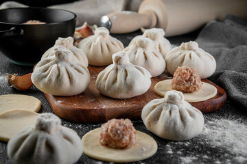 Traditional frozen homemade  georgian khinkali or manty dumplings. Ravioli set on a wooden cutting board on a dark table
