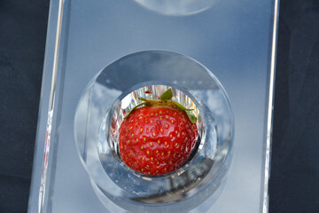 Delicious red strawberries in a glass decorative plate. Blurred industrial background