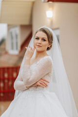 Naklejka premium Portrait of a beautiful bride with a flying veil in a voluminous wedding dress and professional make-up. Close-up portrait of a young gorgeous bride. Wedding.