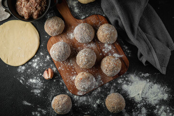 Frozen meatballs with spices on a cutting board on a dark background with flour. Raw ingredients for cooking food