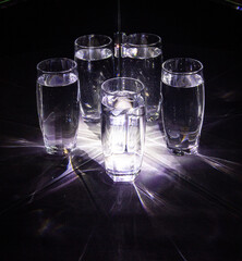 Glass glasses with water reflected in mirrors on a black background