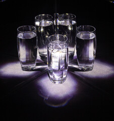 Glass glasses with water reflected in mirrors on a black background