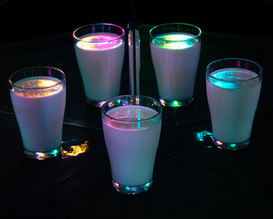 glasses with a milkshake reflected in mirrors and illuminated by colored light