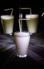 glasses with a milkshake reflected in mirrors and illuminated by colored light