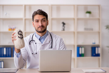 Young male doctor holding moneybag