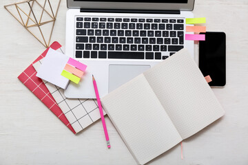 Laptop with phone and different stationery on white wooden background