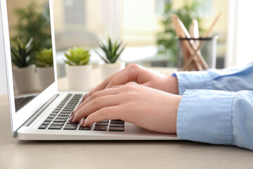 Woman working with modern laptop on comfortable workplace
