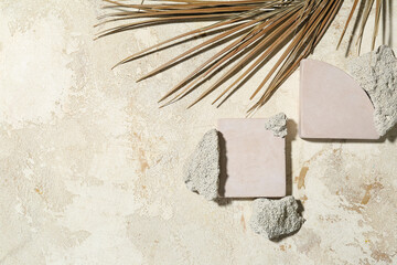 Composition with plaster podiums, stones and dried palm leaf on light background