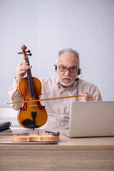 Old male music teacher in the classroom