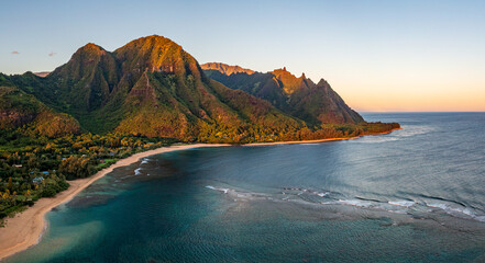Aerial panoramic image of early morning light just catching the mountains dominating Tunnels beach on Hawaiian island of Kauai with Na Pali mountains