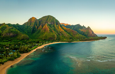 Aerial panoramic image of early morning light just catching the mountains dominating Tunnels beach on Hawaiian island of Kauai with Na Pali mountains