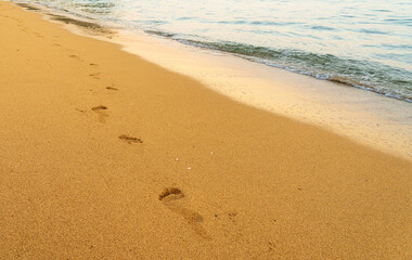 Fototapeta na wymiar Bare footsteps from feet leading along the empty warm sandy beach of Tunnels Beach on Kauai, Hawaii