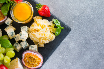 Different sorts of cheese set. Cheese platter with various cheese, grapes, gray background copy space
