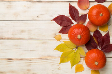 Flat lay with pumpkins, fruits and autumn leaves on wooden background, top view