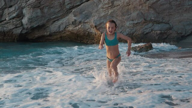 A Child Girl in a Swimsuit and Swimming Glasses Plays on the Sea Beach 