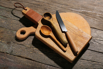 Different cutting boards, spoons and knife on wooden background