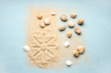 Many pebble stones, seashells and sand on blue background