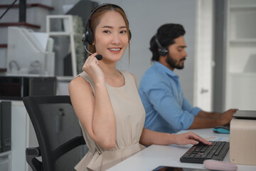 Young woman working in call centre, surrounded by colleagues. Call center workers..