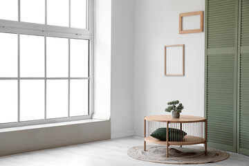 Wooden coffee table with bonsai tree and green folding screen near window