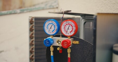 Dolly in close up of yellow safety helmet and manifold gauges used for checking air conditioner...
