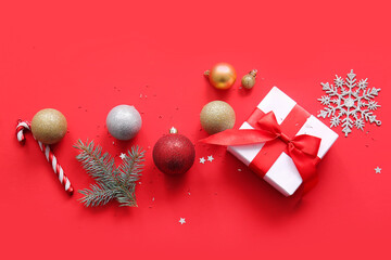 Christmas tree branch with balls and gift box on red background