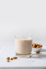 Fresh almond milk in glass and nuts. Altenative plant based vegan milk. Close up.