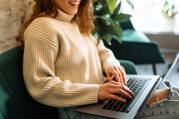 Close-up of female hands typing on a laptop. Working woman in a laptop in a cozy cafe. The concept of freelance, remote work.