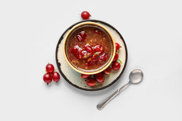 Bowl with tasty gooseberry jam on white background