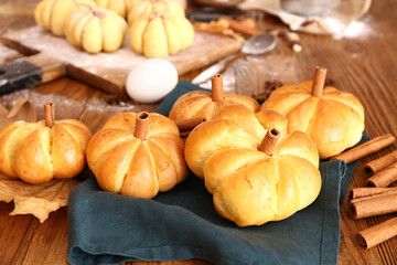 Tasty pumpkin shaped buns on wooden background