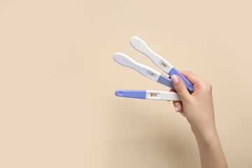 Female hand with pregnancy tests on color background