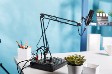 Sound controller console and professional microphone on table at empty blogger workspace. Audio mixer professional equipment on desk in vlogger home studio with no people