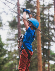 View of high ropes course, kids of climbing in amusement acitivity rope park, passing obstacles and...