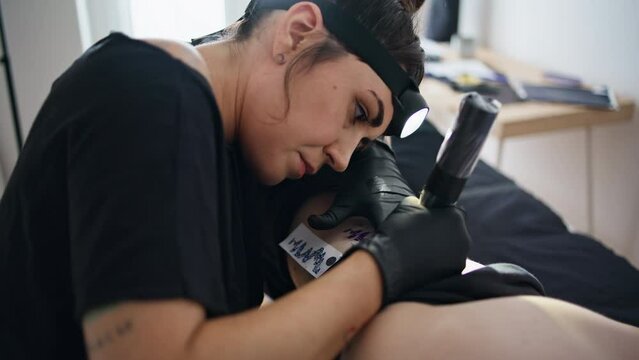 Professional artist tattooing skin salon closeup. Focused woman working machine