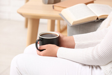 Woman holding cup of tasty coffee at home