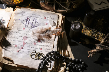 Witch's magic attributes with spell book on dark background, closeup