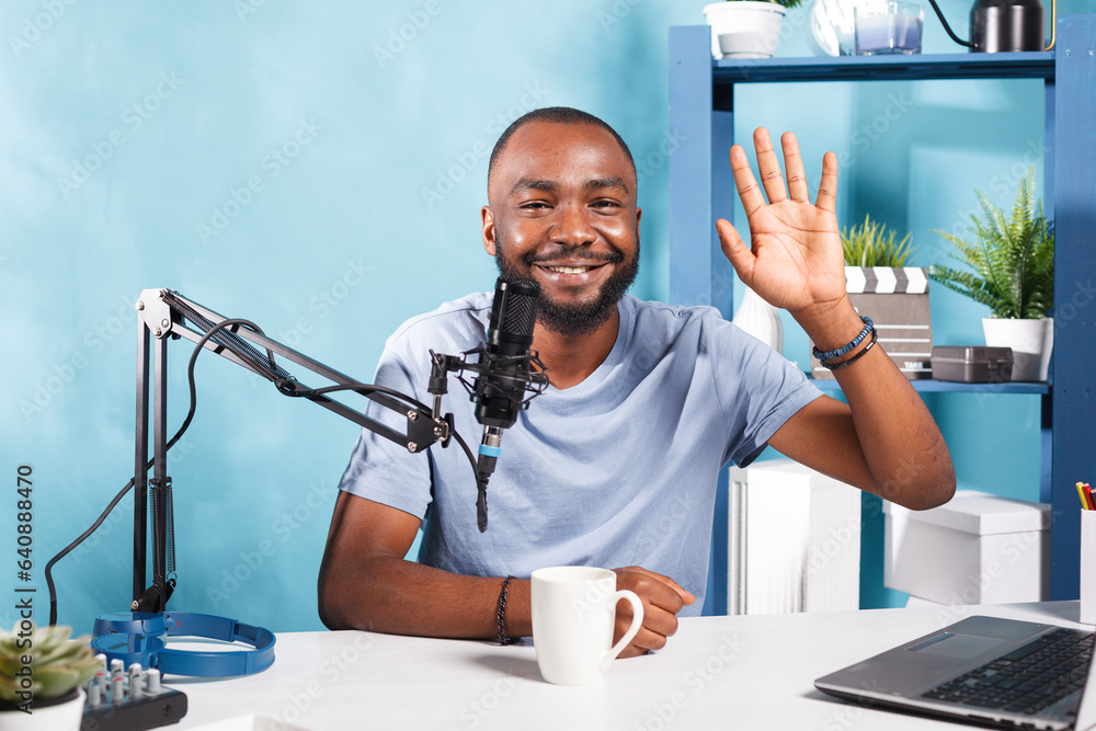 Poster smiling young blogger recording video and streaming on internet channel while greeting subscribers a