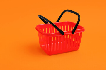 Fototapeta premium Small red shopping basket on orange background