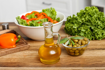 Jug with oil and olives on table in kitchen