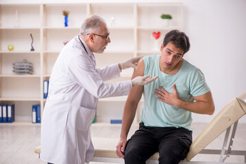 Obraz premium Young male patient visiting old male doctor in vaccination conce