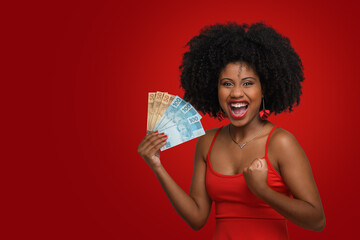 woman holding money, young woman holding brazilian money on red background.