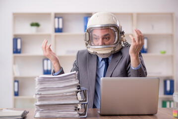 Old male employee wearing spacesuit in the office