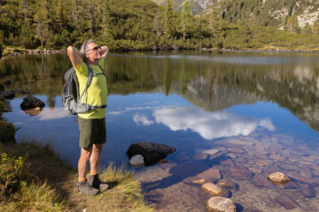 Portrait of an athletic man with a backpack against the background of a mountain lake with a bright...