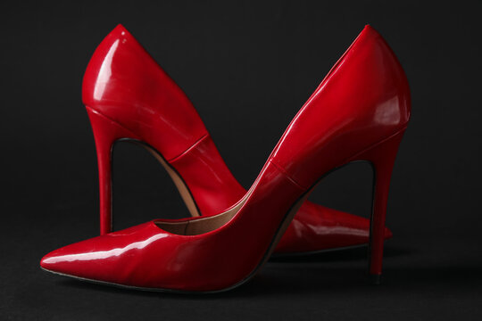 Stylish red high heels on black background