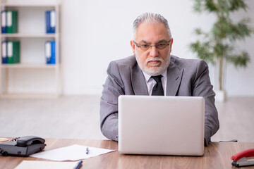 Old male employee working in the office