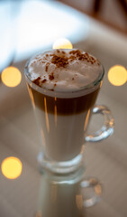 Capuchino servido en tasa de cristal sobre superficie transparente 